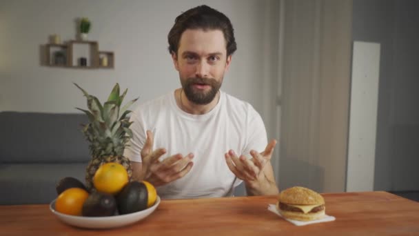 Man legde op camera het verschil uit tussen een gezonde maaltijd en een schadelijke, bijvoorbeeld op fruit en hamburger. - Video