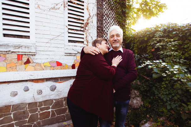 Elderly couple in love walking in the autumn park. Older people hug each other - Valokuva, kuva