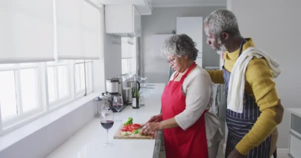 A senior African American couple spending time at home together, social distancing and self isolation in quarantine lockdown during coronavirus covid 19 epidemic, standing in the kitchen, preparing food, embracing and smiling in slow motion - Felvétel, videó