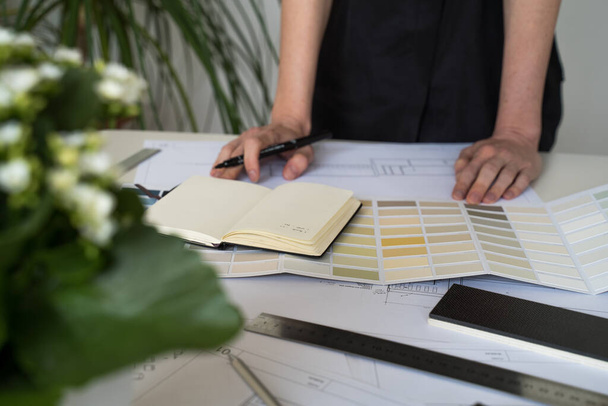 The interior designer selects wall paint samples. Designer at work. Architect desk. Decoration. Design project blueprints. Plans and drawings. Grey stone. Paint catalog. Decorative material. Flatlay - Photo, Image