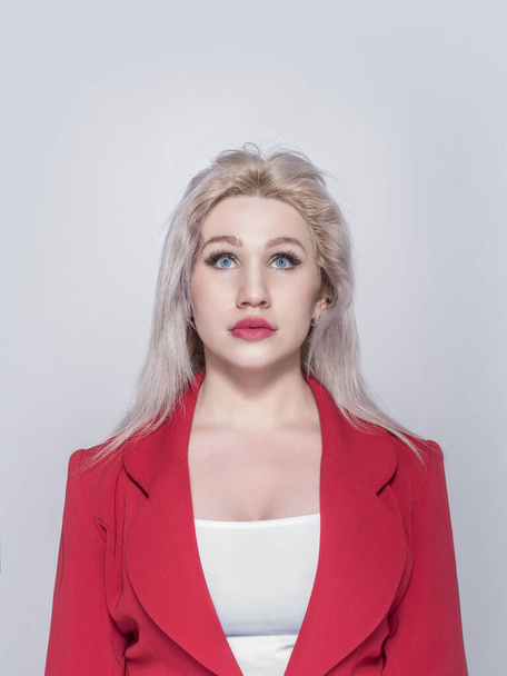 Beautiful young girl, blonde, business woman in a red jacket and suit on a gray background. - Фото, зображення