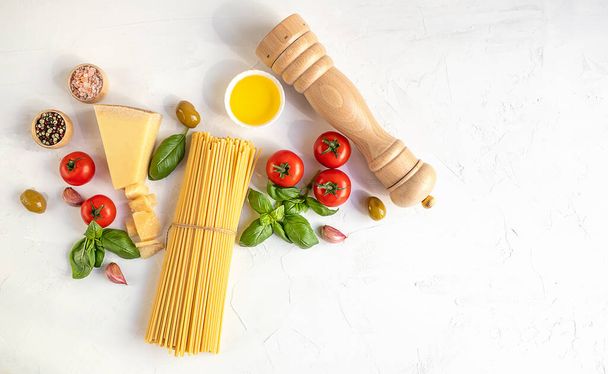 Ingredientes crudos para cocinar pasta italiana tradicional sobre un fondo de hormigón blanco. Espaguetis, vista superior
. - Foto, imagen
