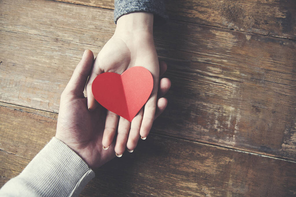 Hombre y mujer pareja tienen un corazón rojo en la mesa de madera
 - Foto, imagen