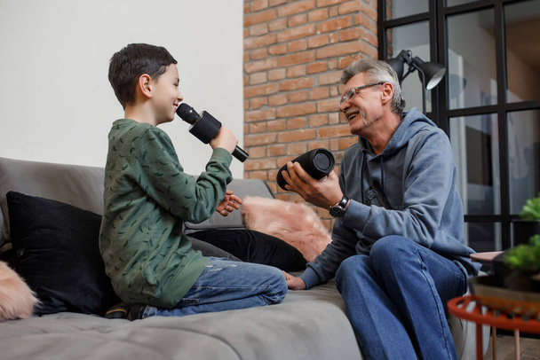 Happy boy and grandfather singing karaoke with with a music column at living room. - Foto, imagen