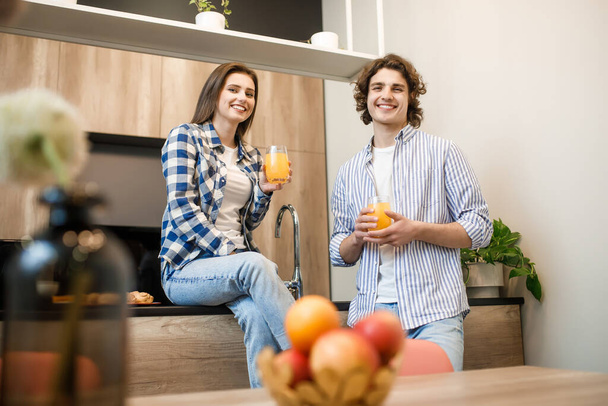 Couple eating breakfast early in the morning in the kitchen and having a good time with fresh juice. - Foto, Bild