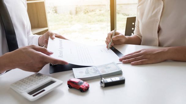 Customer is signing the car rental agreement and getting a car key from dealer after signed in the office, Car rental concept. - Foto, imagen
