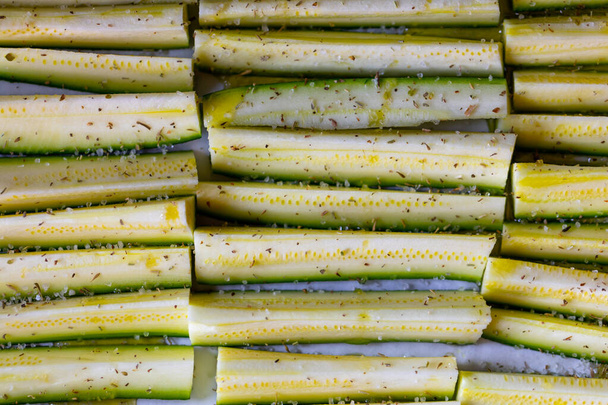 Zucchine fresche tagliate a dadini e condite in primo piano pronte per la cottura disposte in file ordinate in una vista a tutto sesto
 - Foto, immagini