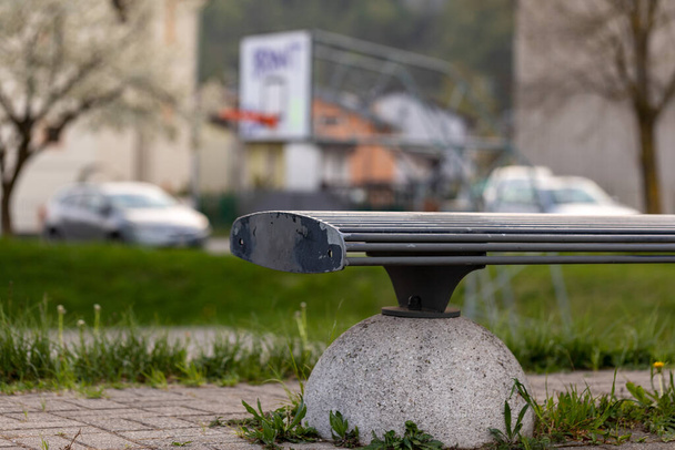 Конец пустой скамейки в городском парке под низким углом с машинами, видимыми на заднем плане в концепции пустых мест из-за блокировки коронавируса или пандемии Ковид-19
 - Фото, изображение