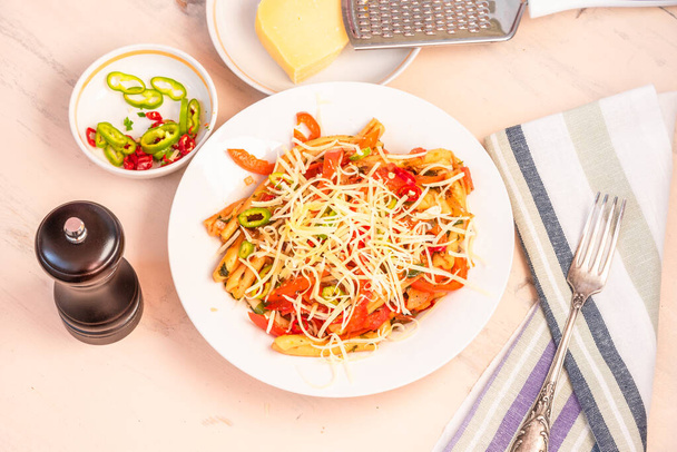 Italské jídlo - těstoviny s červeným pepřem a parmezánem na bílém talíři na rustikálním lehkém stolku, pohled shora - Fotografie, Obrázek