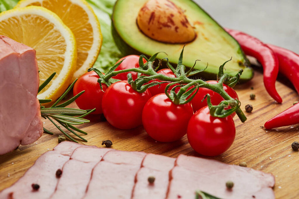 Fresh ripe tomatoes on a cutting board with ham, avocado, peper and lemon - Фото, изображение