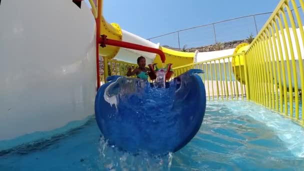 Happy little girl having fun with water splashes in a swimming pool enjoying day trip to a aqua amusement park during summer family vacation - Materiał filmowy, wideo