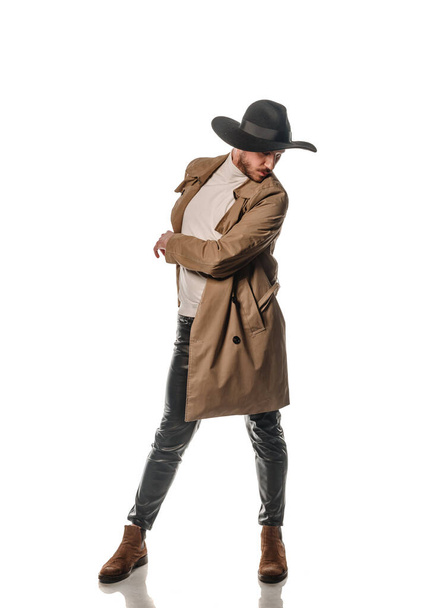 Atrakcyjne młody mężczyzna model pozowanie w skórzane spodnie i długi płaszcz izolowany na biały backgorund - Zdjęcie, obraz