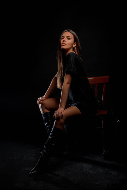 Stylish young woman wearing black leather coat isolated on black background - Photo, image