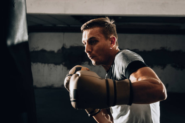 Молодой боксер, занимающийся боксом в спортзале. Кавказский боксер тренируется с боксерской грушей в гимнастике.
 - Фото, изображение