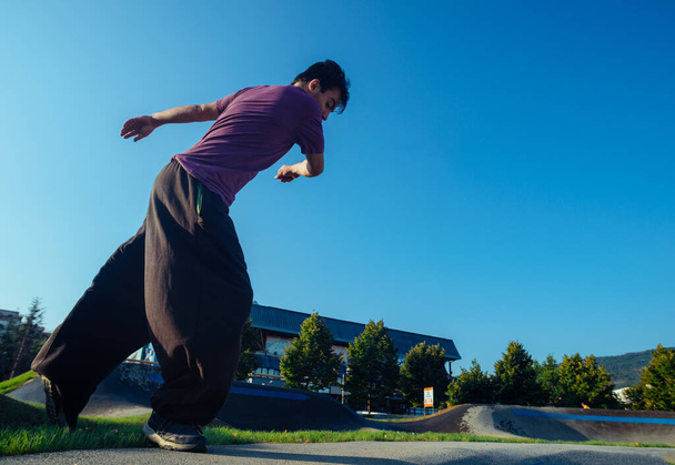 Movimentos de parkour realizados por um acrobático no parque de skate local
 - Foto, Imagem