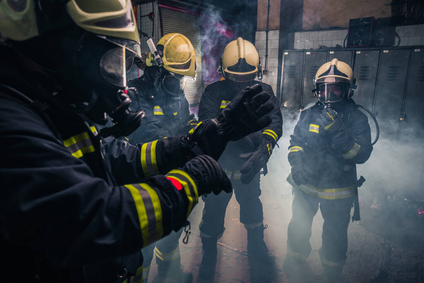 Pompiers en uniforme portant des gants et des masques à gaz à l'intérieur du service d'incendie
 - Photo, image
