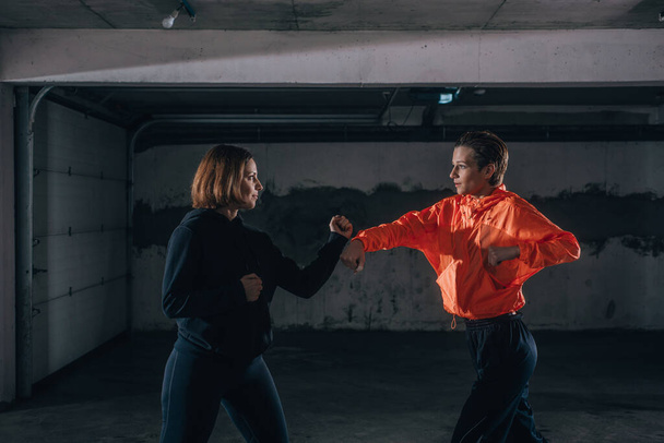 Twee vrouwelijke atleten tonen technische vaardigheden tijdens het oefenen van vechten in een garage - Foto, afbeelding