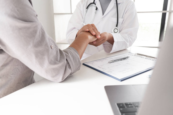 医者と患者だ。テーブルの上に手を取り、座っている間に何かを議論します,医学と医療の概念.   - 写真・画像