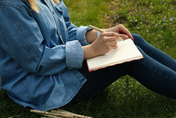 Chica dibuja al aire libre sentado en la hierba verde. Concepto de creatividad
 - Foto, imagen