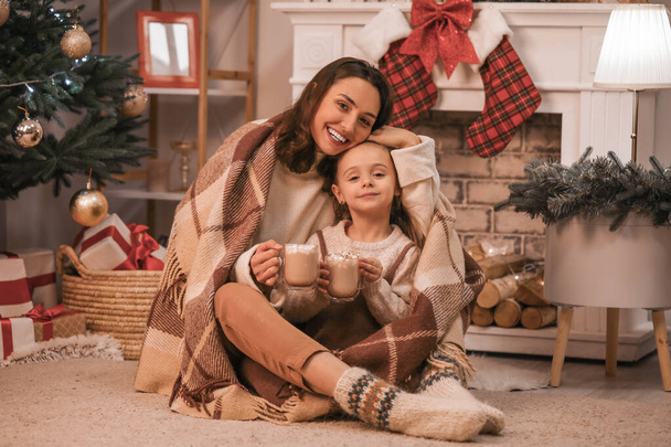 Mulher e sua filha bebendo cacau saboroso em casa na véspera de Natal
 - Foto, Imagem