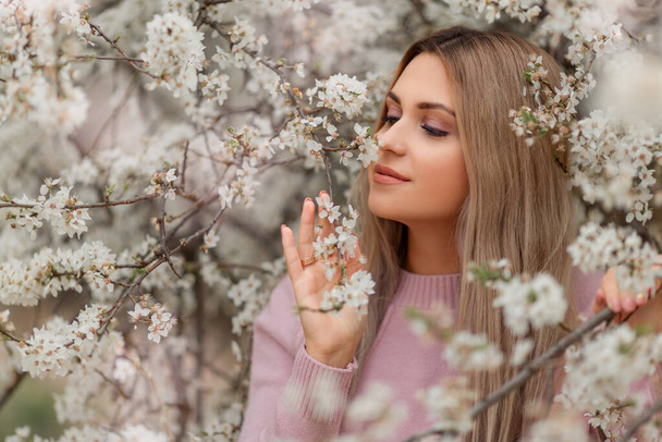 Portrait of young beautiful woman in the flowered blossom garden in the spring time. Almond flowers blossoms - Фото, изображение