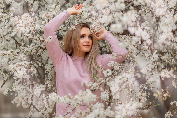 Portrait of young beautiful woman in the flowered blossom garden in the spring time. Almond flowers blossoms - Fotografie, Obrázek