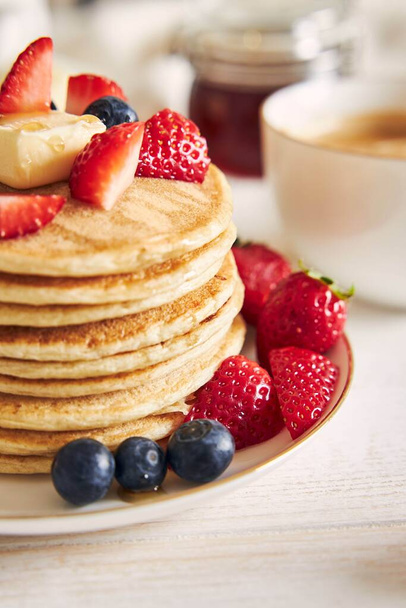 A vertical shot of vegan pancakes with fruits on a white plate - Foto, Bild