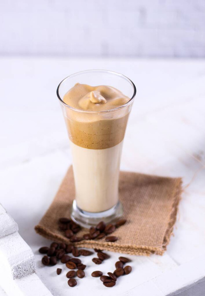 A vertical shot of a caramel smoothie on a brown napkin surrounded by coffee beans - Фото, изображение