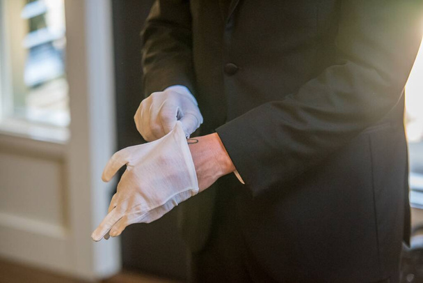 A shallow focus shot of a man in a black tuxedo wearing white gloves - Zdjęcie, obraz