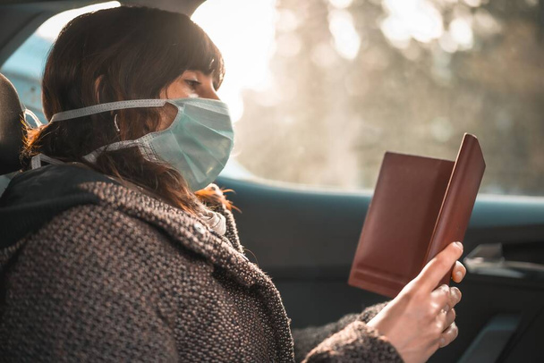 A woman in a medical mask looking at her opened phone case - 写真・画像