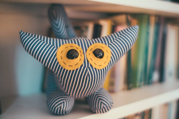 A closeup selective shot of an owl pillow with huge yellow eyes - Foto, Imagen