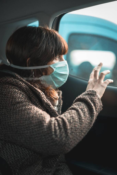 Eine vertikale Aufnahme einer Frau mit medizinischer Maske im Auto während der Quarantäne - Foto, Bild