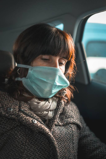 A vertical shot of a woman with a medical mask in the car during the quarantine period - Photo, image