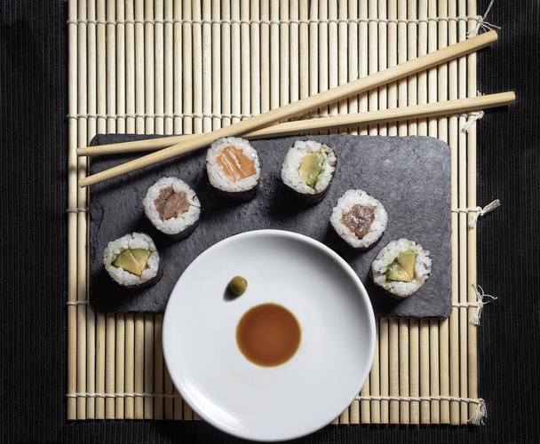 Sushi, sur une assiette carrée décorée de sauce soja et de baguettes
 - Photo, image