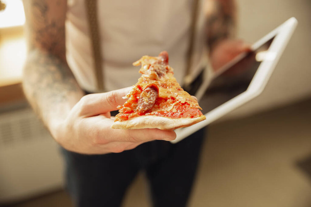Close up of male hands holding pizza and tablet, proposing - Foto, Bild