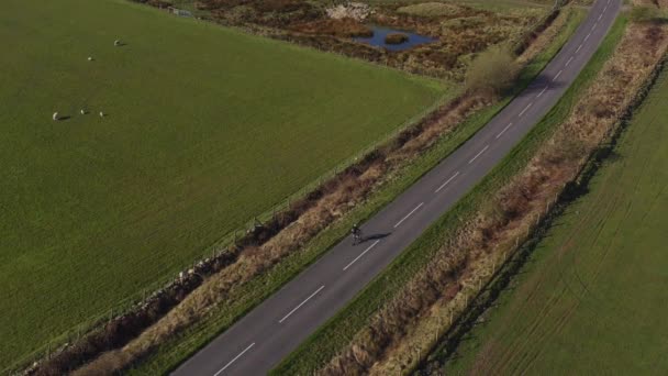 Drohnenaufnahmen einer Person beim Mountainbiken auf einer leeren Landstraße an einem sonnigen Morgen in North Yorkshire England völlig isoliert - Filmmaterial, Video