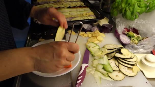 Příprava míchané zeleniny nakrájené na tenké plátky, naolejované a vložené do pánve k pečení. Lilek, rajčata, brambory, cukety a červená cibule - Záběry, video