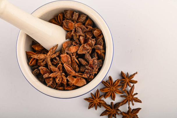 star anise in a blue ceramic spice mortar with a pestle on a white background. Close up - Photo, Image