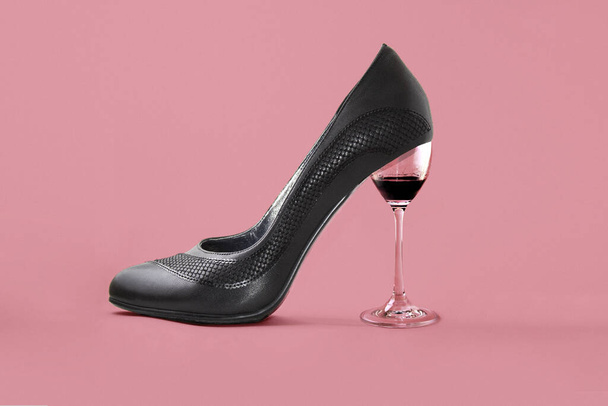 women's shoes and a glass of wine on a pink background, a glass of wine replaces the heel of the Shoe. the concept of femininity, freedom, and celebration. - Foto, afbeelding