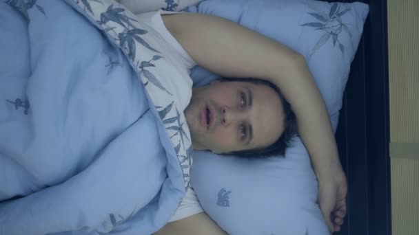 Widok z góry. zbliżenie. Młody człowiek w łóżku cierpiący na bezsenność. pionowo - Materiał filmowy, wideo