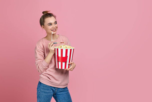 beautiful young woman eating popcorn from bucket - Foto, afbeelding
