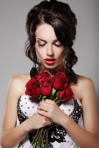 Jonge schoonheid ruikt boeket van rode rozen. Genot & Harmonie - Foto, afbeelding