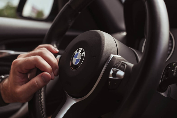 Bologna, Italy, May 15, 2019, the city of Bologna. BMW car steering wheel. Male hand in the frame - 写真・画像