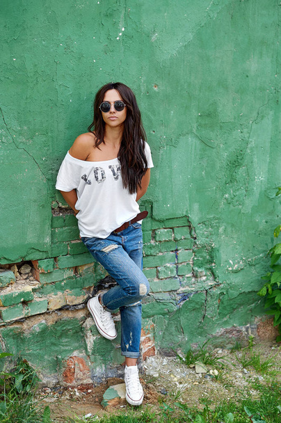 Outdoor street fashion portrait of stylish beautiful woman posing in blue jeans and sunglasses - Foto, Imagem