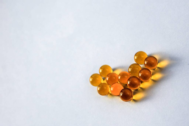 Yellow capsules of vitamins omega 3 fatty acids lie on a table on a white background isolated for immunity and disease prevention in the shape of a heart - Foto, Imagem