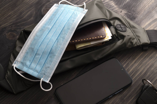 A man's everyday essentials with a  face mask, wallet and smart phone. Corona Virus Time - Фото, изображение