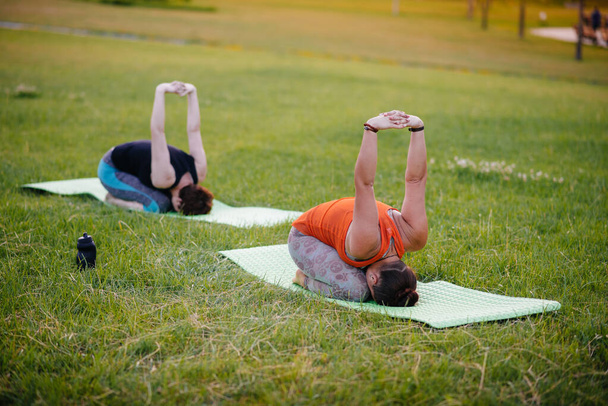 A fiatal lányok jógáznak a parkban napnyugtakor. Egészséges életmód - Fotó, kép