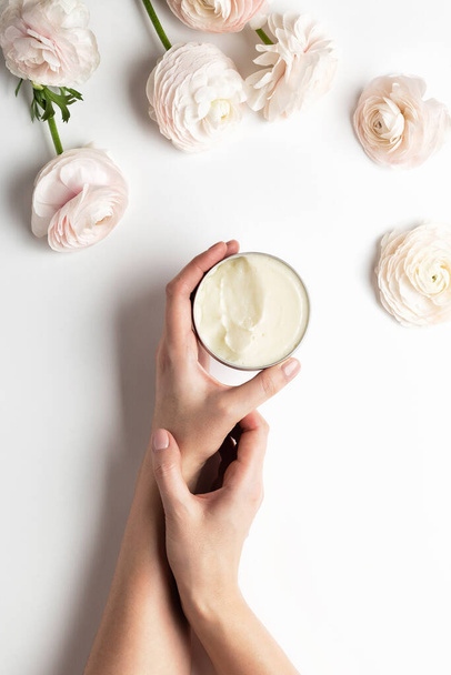 Corps cosmétique ou récipient à crème pour le visage avec soin produit sans cruauté. ranunculus rose pastel sur fond de marbre blanc, plan plat ou vue sur le dessus
 - Photo, image