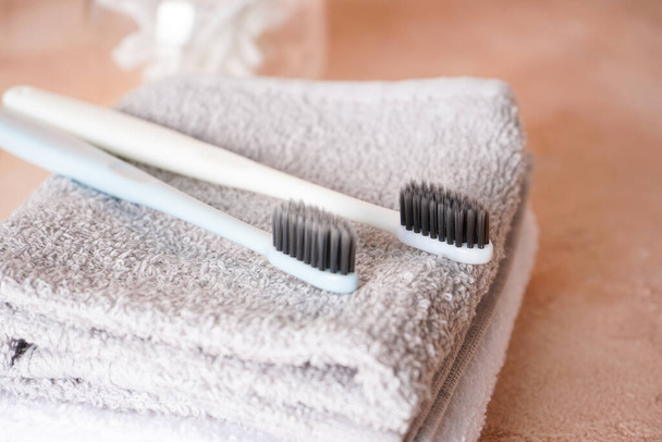 Two toothbrushes with black shield and towels, on a beige background - Foto, Imagen