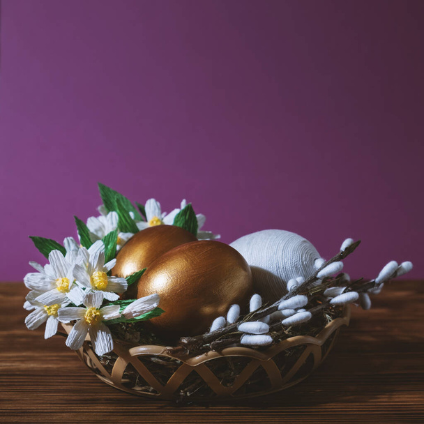 Easter eggs in basket filled with straw and yellow flowers and willow. Preparation for holiday. Easter decorations - Foto, immagini